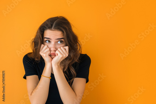 femme découragée assise la tête dans ses mains le regard perdu sur fond orange, espace pour texte