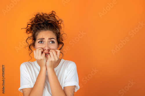 Femme anxieuse se rongeant les ongles sur un fond orange, espace pour texte photo