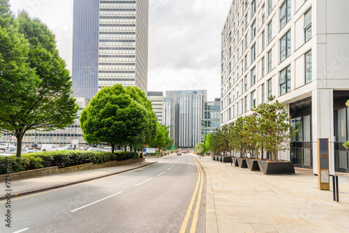 Street lined with modern office buildings and parking lots in a city centre on a cloudy summer day