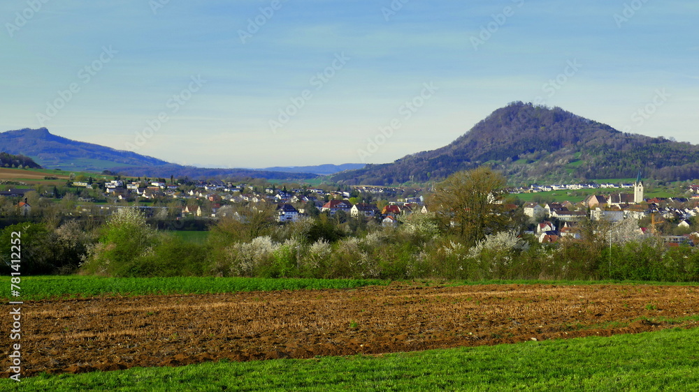 Panorama auf Engen im Hegau im Frühling mit Feldern, Bergen und blühenden Bäumen unter blauem Himmel