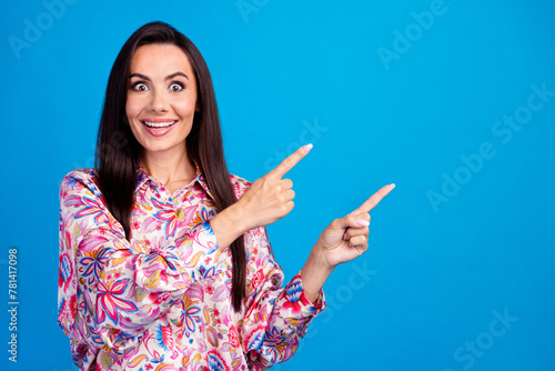 Photo of adorable excited lady dressed print blouse showing two fingers emtpy space isolated blue color background photo