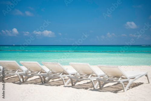 The row of empty sun loungers on a beautiful tropical beach with white sand and turquoise sea water without people. The best summer vacations ideas and destinations. Caribbean copy space background  © Bankerok