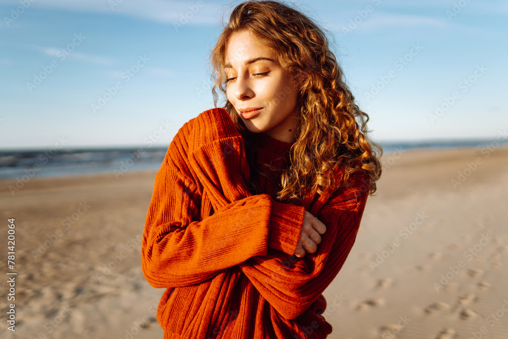 Outdoor portrait of pretty woman on the beach in cold sunny weather. Travel, fashion, blogging concept. Outdoor portrait of pretty woman on the beach in cold sunny weather. Travel, fashion, blogging concept.