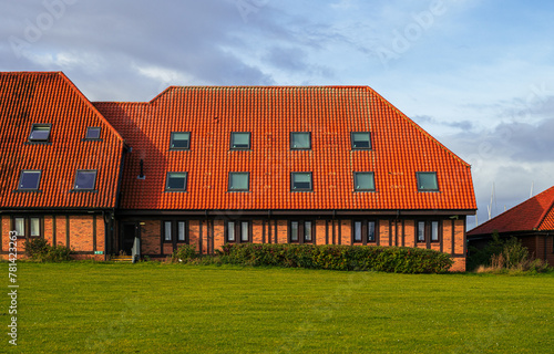 Large building on green field with orange roof tiles and attic skylights