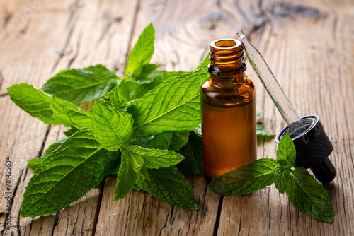 Bottle of mint essential oil and mint green leaves