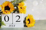 Special Recreation for the Disabled Day. White wood calendar blocks with the date July 2nd and beautiful sunflower bouquet with bokeh. Selective focus with blurred background. 