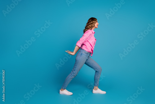 Full body photo of pretty young girl carry back empty space wear trendy pink outfit hairdo isolated on blue color background © deagreez