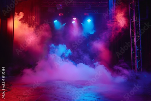 A dramatic stage clouded with thick smoke under blue and pink spotlights  suggesting anticipation before an event.  