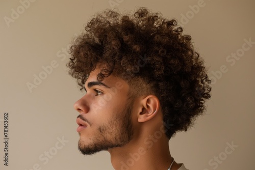 Profile view of a young man displaying a stylish curly undercut hairstyle on a neutral background photo