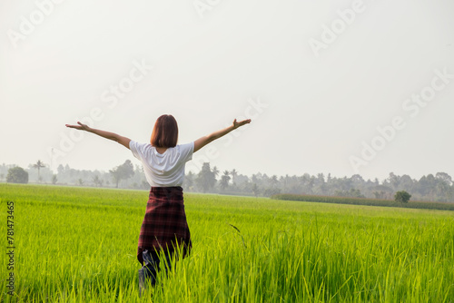 A joyful woman leaps in a sunny meadow, embodying freedom and happiness in nature © Thannaree