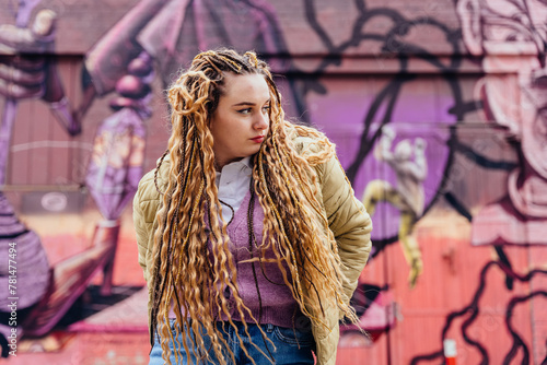 Effervescent energy meets urban chic as a vibrant young woman poses against a backdrop of colorful graffiti-filled walls