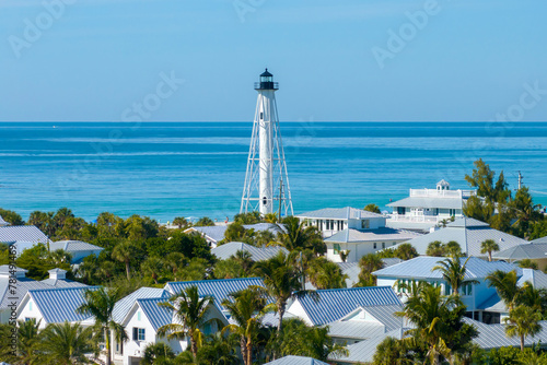 Boca Grande, Florida. Lighthouse on ocean shore for commercial vessels navigation. Expensive waterfront houses between green palm trees on Gasparilla Island photo