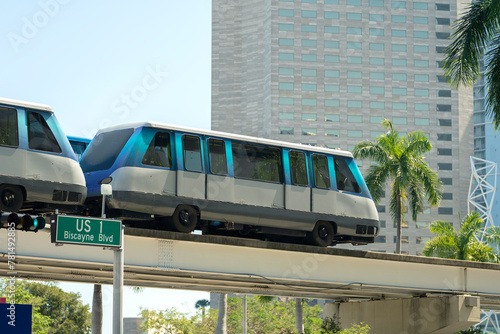 City train car on high railroad over street traffic between skyscraper buildings in modern American megapolis. Urban transportation in downtown district of Miami Brickell in Florida USA