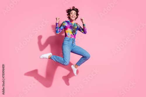 Full size photo of nice young woman jump raise fists wear pullover isolated on pink color background © deagreez