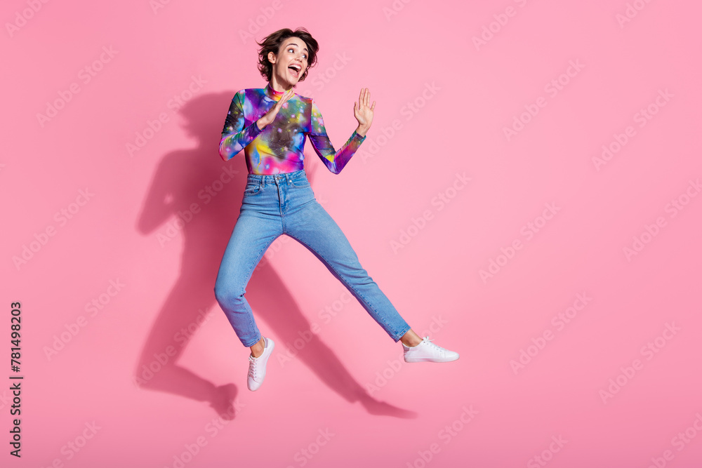 Full size photo of nice young woman jump look empty space wear pullover isolated on pink color background Full size photo of nice young woman jump look empty space wear pullover isolated on pink color background