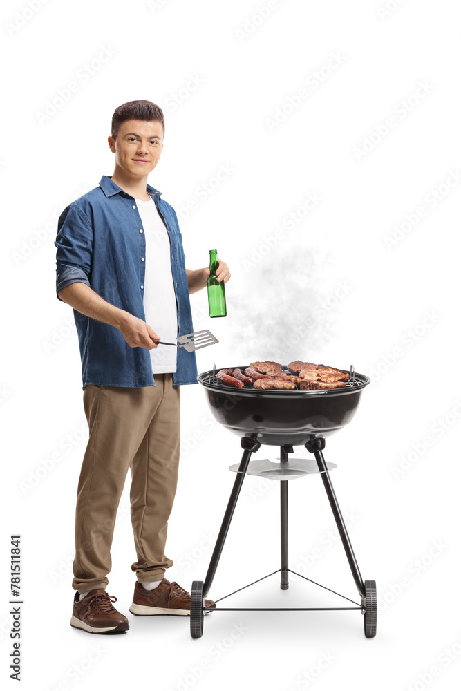 Young man making a barbecue and holding a bottle of beer - obrazy, fototapety, plakaty 