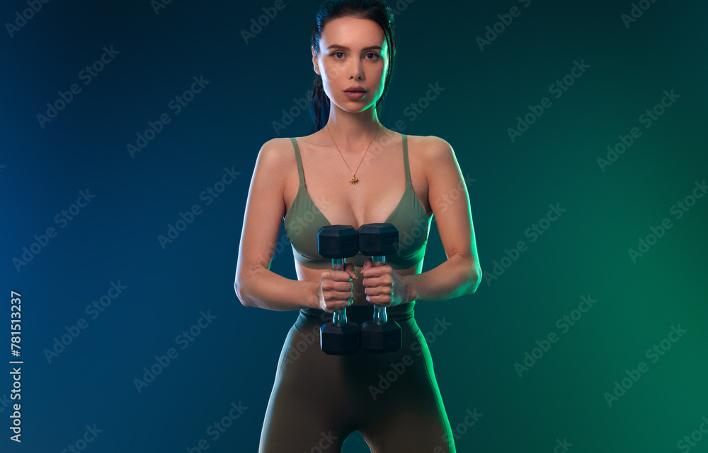 Obraz premium Sporty fit woman, athlete with dumbbells make fitness exercises on neon background. Download cover for music collection for fitness classes. Sports recreation. Beautiful black young woman.