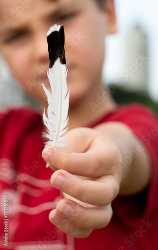 Um menino mostra em suas mãos  uma asa branca e preta photo