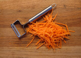 grated carrots and grater on a wooden cutting board