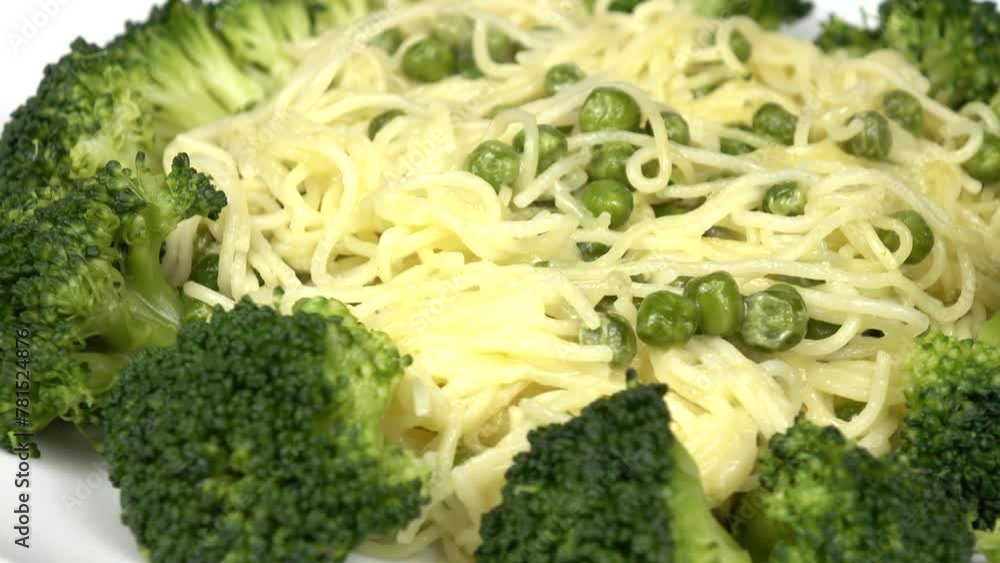 Italian spaghetti with green peas, broccoli and grated cheese parmesan lie on a white plate 