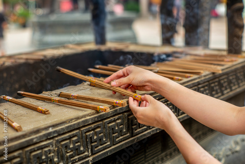 Hands of a woman holding burning incense sticks in the Jing'an temple in Shanghai