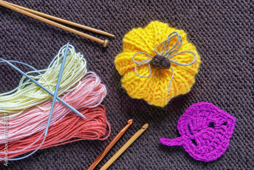 Hobby and knitting concept. Knitted pumpkin, kniitting neadles, crochet hooks on knitted background