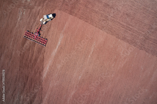 Sowing campaign. Tractor with trailed combined tillage machine working on a field with red soil. Drone footage. photo