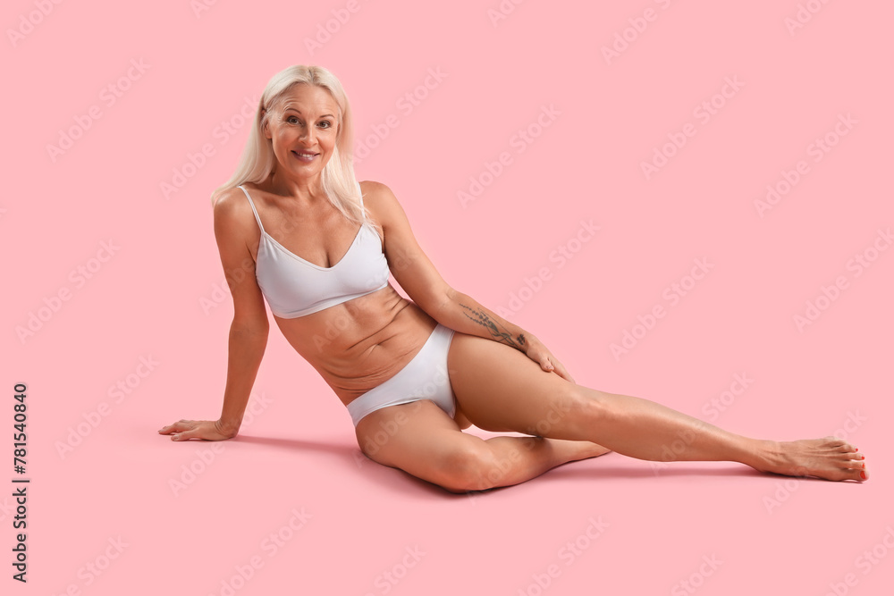 Body positive mature woman in underwear sitting on pink background Body positive mature woman in underwear sitting on pink background