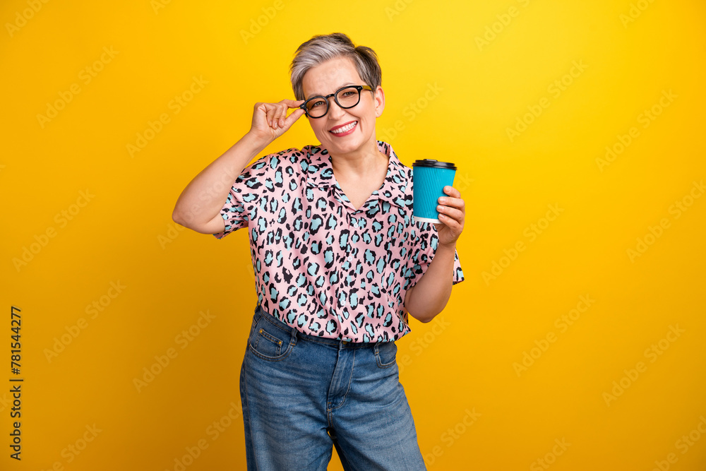 Photo portrait of lovely senior lady hold coffee paper cup drink dressed stylish leopard print garment isolated on yellow color background - obrazy, fototapety, plakaty 