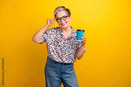 Photo portrait of lovely senior lady hold coffee paper cup drink dressed stylish leopard print garment isolated on yellow color background