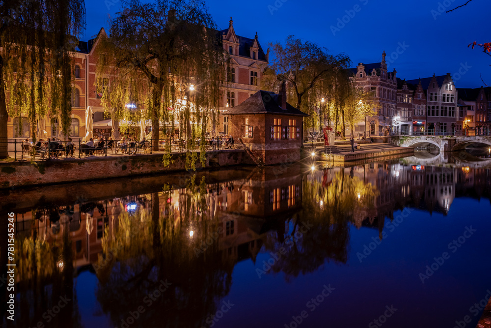 Lier city in Belgium at night. warm lights reflect on water at evening people eat and drink in street of old houses historic building Buyldragershuisje. nightlife on Feix timmermansplein square