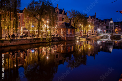 Lier city in Belgium at night. warm lights reflect on water at evening people eat and drink in street of old houses historic building Buyldragershuisje. nightlife on Feix timmermansplein square