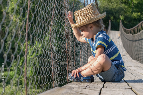 Suspension bridge. The boy sits and looks over the fence. It does not move forward (Concept: limitations in our head)