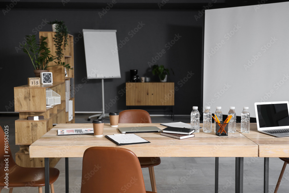 Wooden table, armchairs and stationery prepared for business meeting in modern conference hall Wooden table, armchairs and stationery prepared for business meeting in modern conference hall