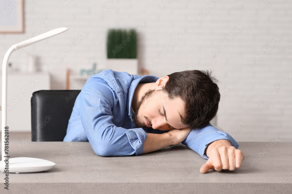 Tired young businessman sleeping at table in office Tired young businessman sleeping at table in office