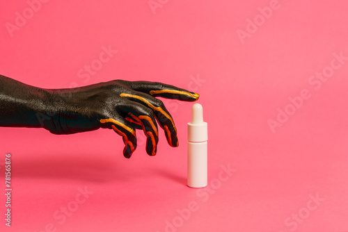 Black and gold painted elegant hand on skin with cosmetic unbranded bottle. Luxury, high fashion cosmetic products concept