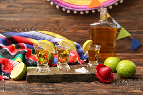 Bottle of tequila with shots and lime on color background