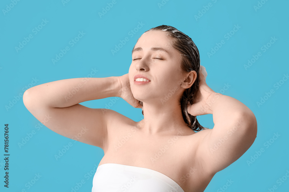 Beautiful young woman washing hair on blue background Beautiful young woman washing hair on blue background