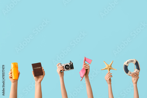 Female hands with sunscreen, decorative lifebuoy, photo camera, passport, heeled sandal and starfish on blue background. Travel concept.
