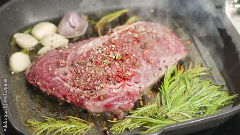 Ribeye steak with herbs and garlic are being roasted on the grill pan. Ribeye steak with herbs and garlic are being roasted on the grill pan.