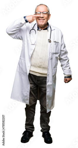 Handsome senior doctor man wearing medical coat Pointing with hand finger to face and nose, smiling cheerful