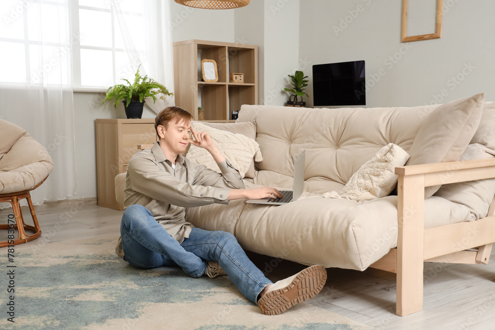 Young man using laptop on couch at home Young man using laptop on couch at home