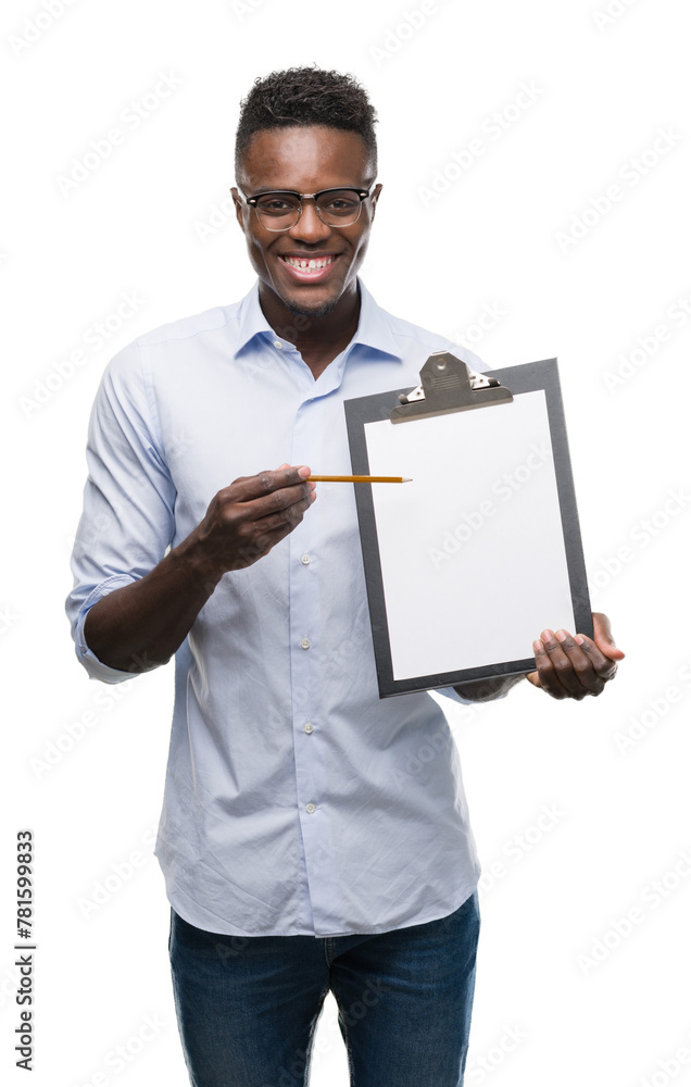 Young african american man holding a clipboarad with a happy face standing and smiling with a confident smile showing teeth Young african american man holding a clipboarad with a happy face standing and smiling with a confident smile showing teeth