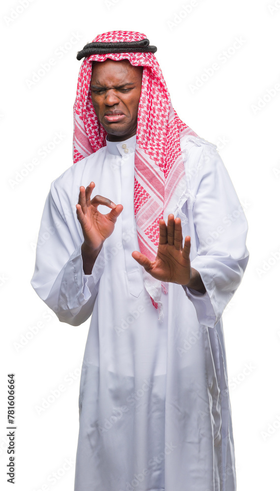 Young arabic african man wearing traditional keffiyeh over isolated background disgusted expression, displeased and fearful doing disgust face because aversion reaction. With hands raised.