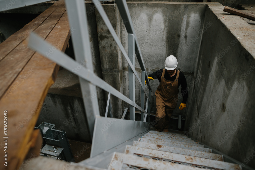 A construction engineer climbs a metal ladder at the construction site of a grain silo. A construction engineer climbs a metal ladder at the construction site of a grain silo.