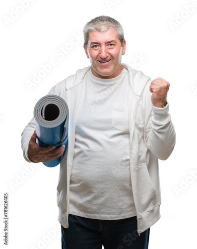 Handsome senior man holding yoga mat over isolated background screaming proud and celebrating victory and success very excited, cheering emotion