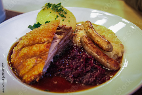 Traditional Bavarian food plate - fried Nurnberg sausages, baked knuckle, potato dumplings and stewed sauerkraut