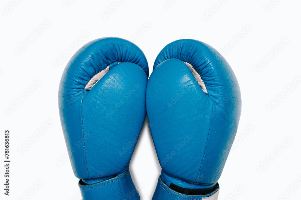 A pair of blue leather boxing gloves close-up top view. Blue boxing gloves isolated on white background. Boxing accessories A pair of blue leather boxing gloves close-up top view. Blue boxing gloves isolated on white background. Boxing accessories
