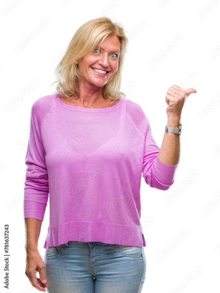 Middle age blonde woman over isolated background smiling with happy face looking and pointing to the side with thumb up. Middle age blonde woman over isolated background smiling with happy face looking and pointing to the side with thumb up.
