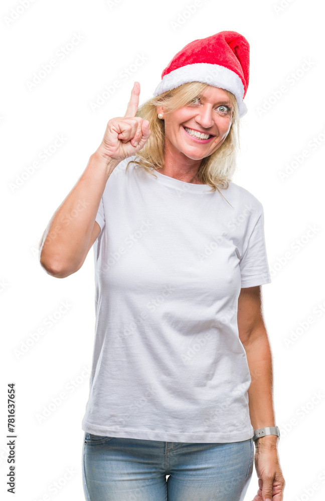 Middle age blonde woman wearing christmas hat over isolated background pointing finger up with successful idea. Exited and happy. Number one. Middle age blonde woman wearing christmas hat over isolated background pointing finger up with successful idea. Exited and happy. Number one.